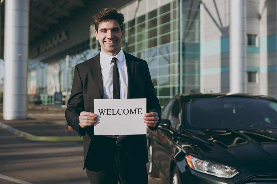 Image shows a young man holding a welcome sign. Meet and greet with Copenhagen Luggage Service takes care of luggage hassle so you can get the most out of your stay in Copenhagen